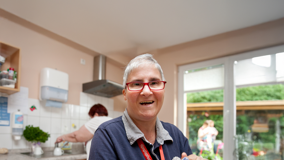 Eine frau mit Brille trocknet Geschirr ab.