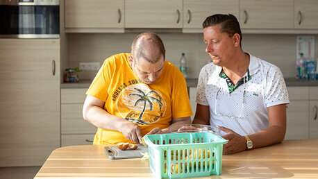 Zwei Männer sitzen am Tisch und bereiten Essen vor